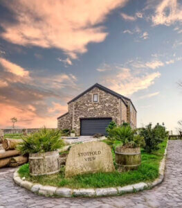 Soft-stone façade and charcoal slate roof blending modern and rural design.