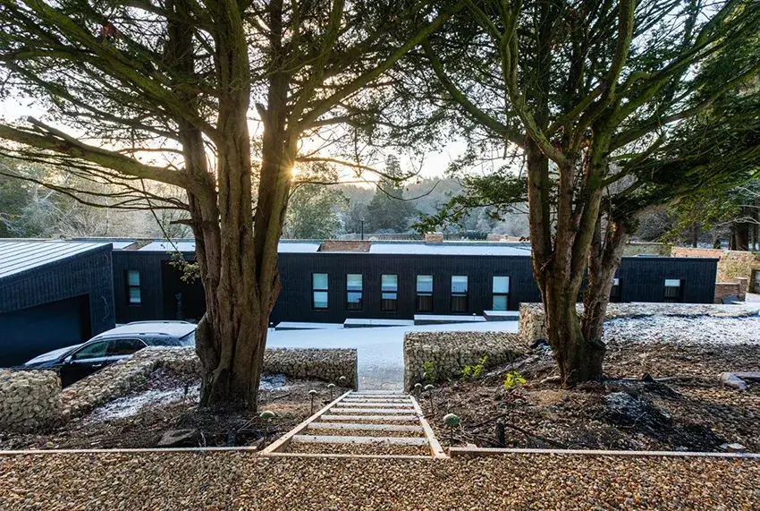Front elevation of Beamish Passive House featuring black timber cladding, stone walls and a low-profile contemporary design.