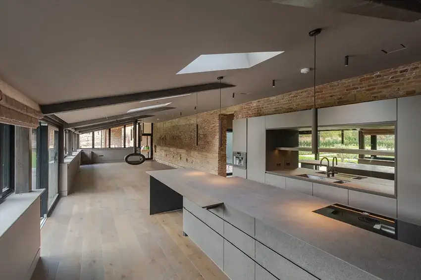 Open-plan kitchen and living area at Beamish Passive House with exposed brickwork, rooflights and large glazed openings.